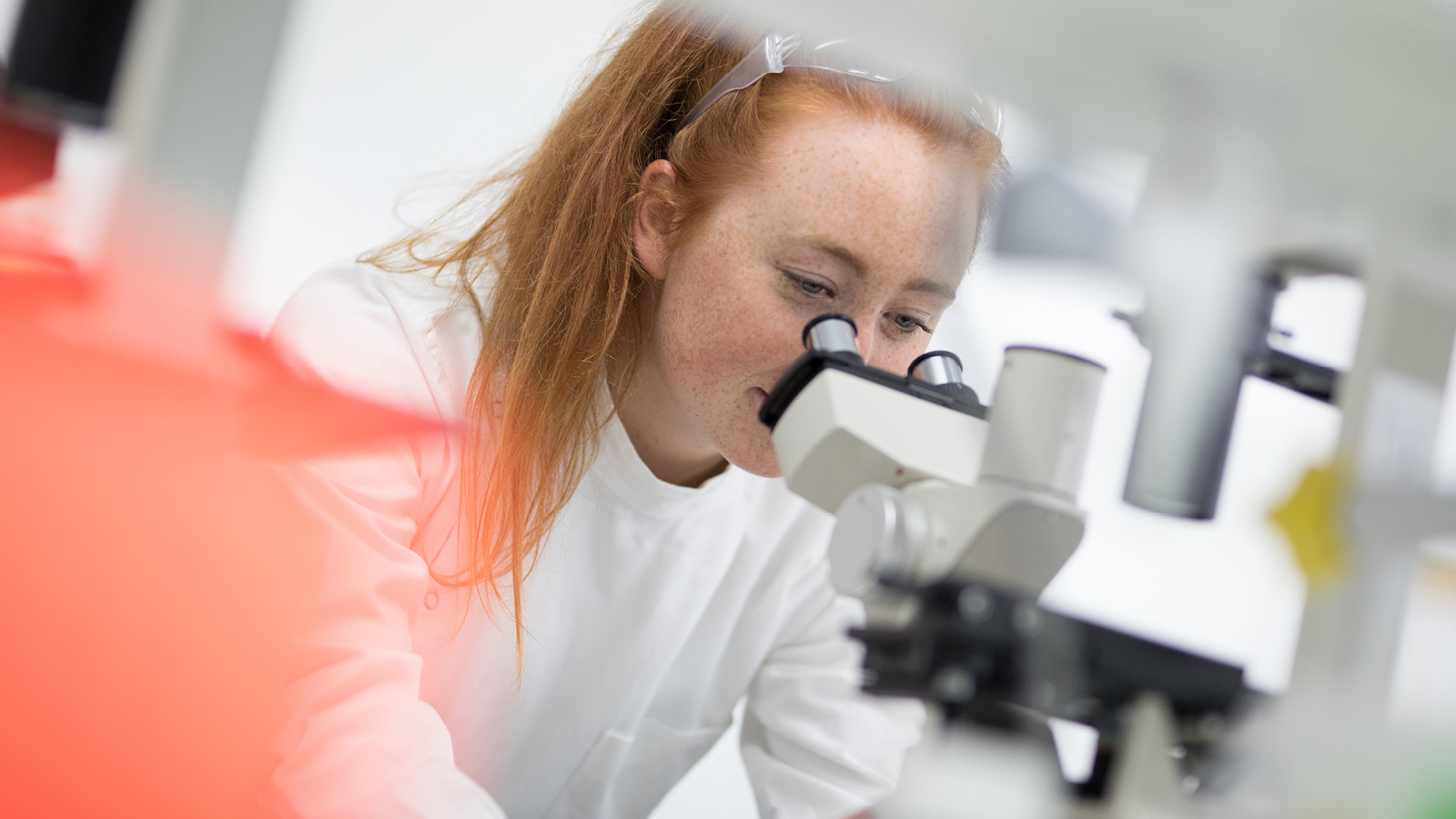 A young woman looking through microscope.