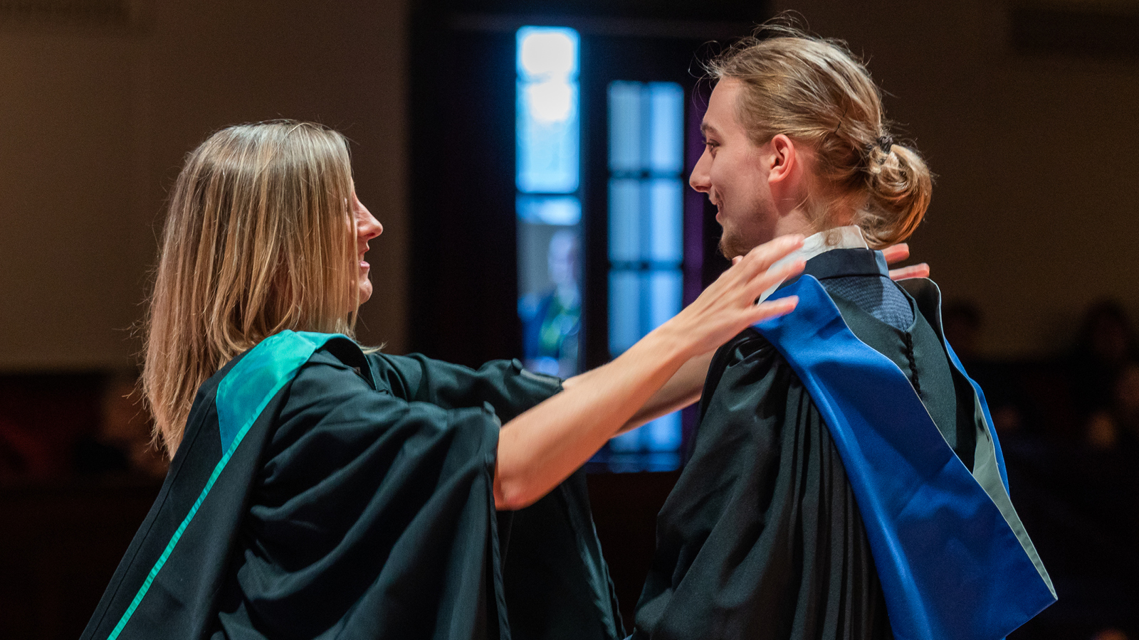 Two graduates wearing graduate gowns.