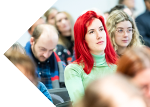 Researchers in a conference room. A woman with bright red hair is in the centre.