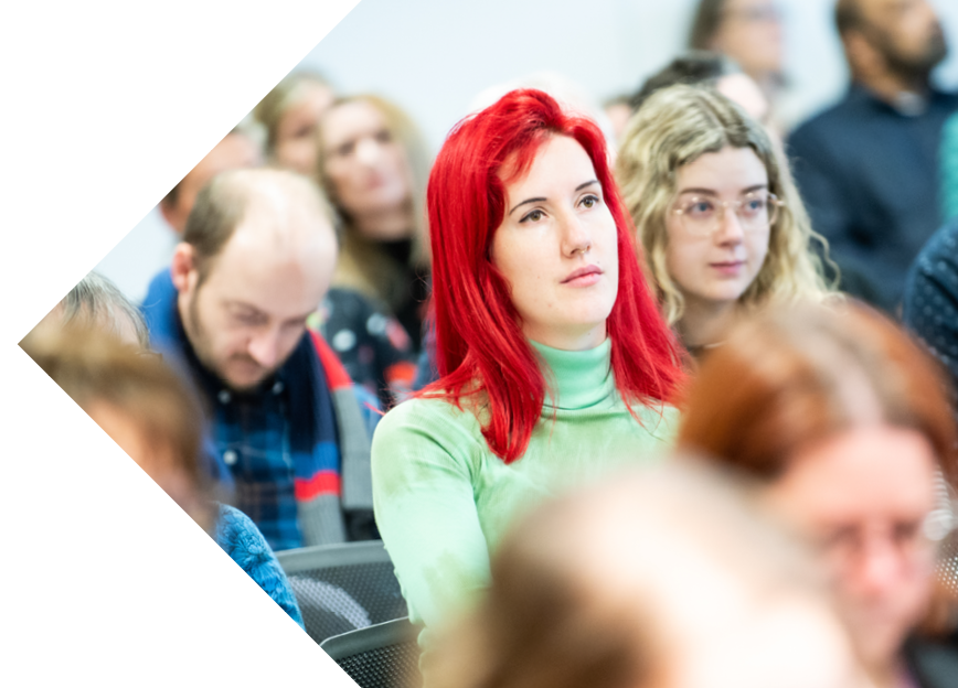 Researchers in a conference room. A woman with bright red hair is in the centre.