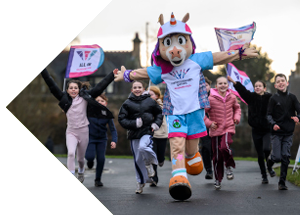 Glasgow 2026 Commonwealth Games mascot running with a group of children carrying event flags.
