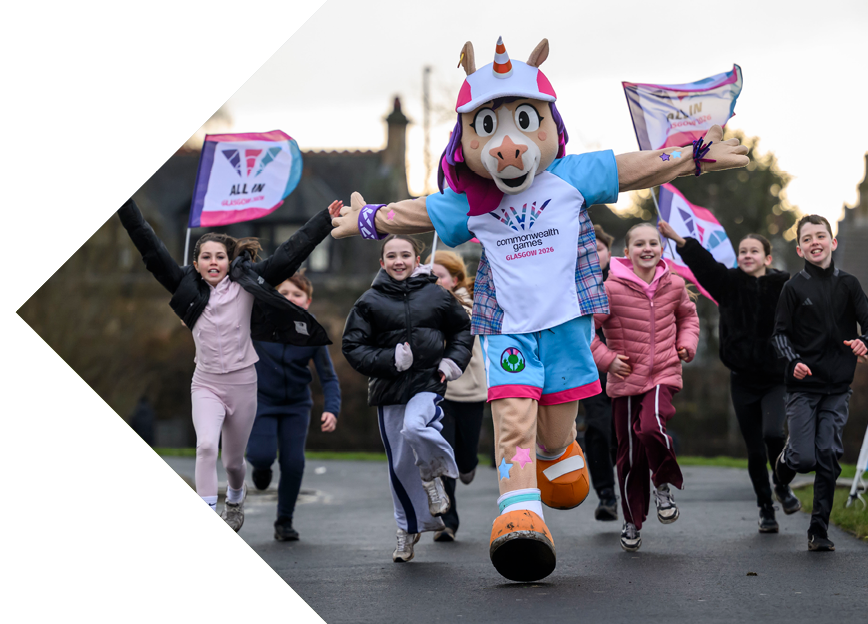 Glasgow 2026 Commonwealth Games mascot running with a group of children carrying event flags.